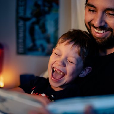 Man en jongen kijken lachend in een boek