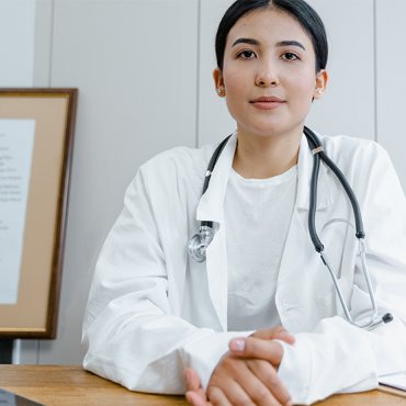 Vrouwelijke arts met stethoscoop aan bureau