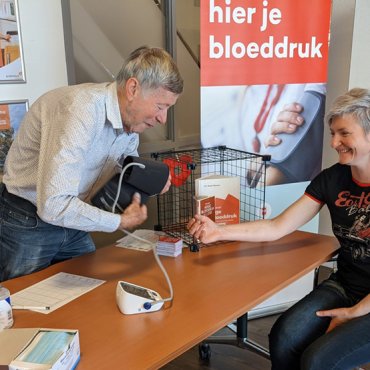 Vrijwilliger meet bloeddruk van bezoeker in de bibliotheek