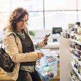 Vrouw met rekenmachine bij schap in supermarkt